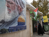 A veiled Iranian woman walks under Lebanon's Hezbollah and Palestine flags while arriving to take part in a charity ceremony for donating go...