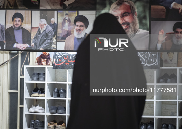 A veiled Iranian woman stands in front of a banner featuring portraits of Lebanon's Hezbollah leader, Hassan Nasrallah, who was killed in an...