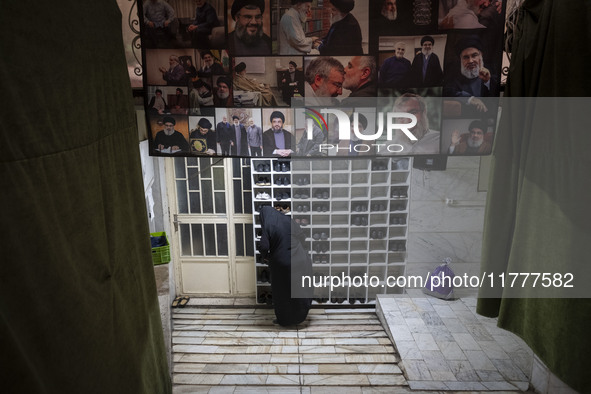 A veiled Iranian woman stands under a banner featuring a portrait of Lebanon's Hezbollah leader, Hassan Nasrallah, who was killed in an Isra...