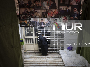 A veiled Iranian woman stands under a banner featuring a portrait of Lebanon's Hezbollah leader, Hassan Nasrallah, who was killed in an Isra...