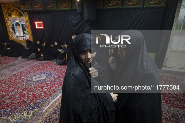 Two veiled Iranian women talk to each other while arriving to take part in a charity ceremony for donating gold and money to help the Lebane...