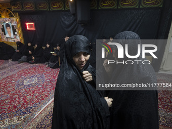 Two veiled Iranian women talk to each other while arriving to take part in a charity ceremony for donating gold and money to help the Lebane...