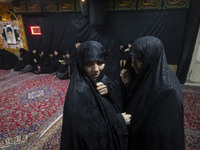 Two veiled Iranian women talk to each other while arriving to take part in a charity ceremony for donating gold and money to help the Lebane...