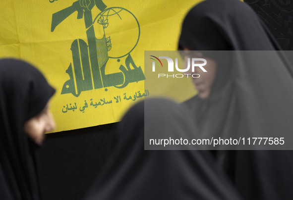 Veiled Iranian women talk to each other while standing in front of a flag of Lebanon's Hezbollah as they arrive to take part in a charity ce...