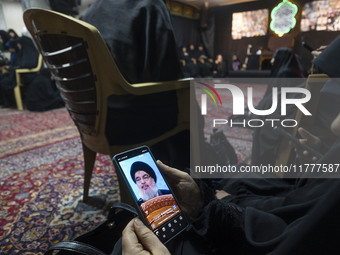 A veiled Iranian woman uses her cellphone featuring a portrait of Lebanon's Hezbollah leader, Hassan Nasrallah, in a suburb of Beirut, while...