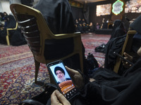 A veiled Iranian woman uses her cellphone featuring a portrait of Lebanon's Hezbollah leader, Hassan Nasrallah, in a suburb of Beirut, while...