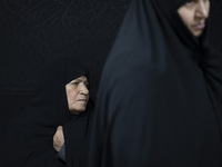 A veiled elderly Iranian woman looks on while participating in a charity ceremony for donating gold and money to help the Lebanese Resistanc...