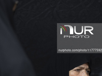 A veiled elderly Iranian woman looks on while participating in a charity ceremony for donating gold and money to help the Lebanese Resistanc...