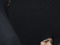 A veiled elderly Iranian woman looks on while participating in a charity ceremony for donating gold and money to help the Lebanese Resistanc...