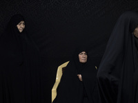 A veiled elderly Iranian woman looks on while participating in a charity ceremony for donating gold and money to help the Lebanese Resistanc...