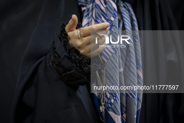 A young veiled Iranian girl holds her gold necklace for a photograph while participating in a charity ceremony to donate gold and money to h...