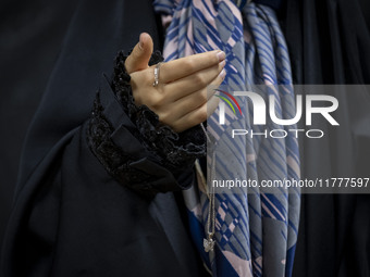 A young veiled Iranian girl holds her gold necklace for a photograph while participating in a charity ceremony to donate gold and money to h...