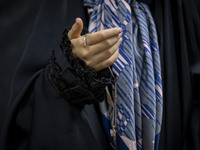 A young veiled Iranian girl holds her gold necklace for a photograph while participating in a charity ceremony to donate gold and money to h...