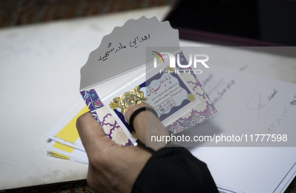 A veiled Iranian woman holds a donated gold plaque with a Persian script on its cover that reads, ''Donated by the martyr's mother,'' during...