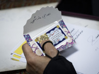 A veiled Iranian woman holds a donated gold plaque with a Persian script on its cover that reads, ''Donated by the martyr's mother,'' during...