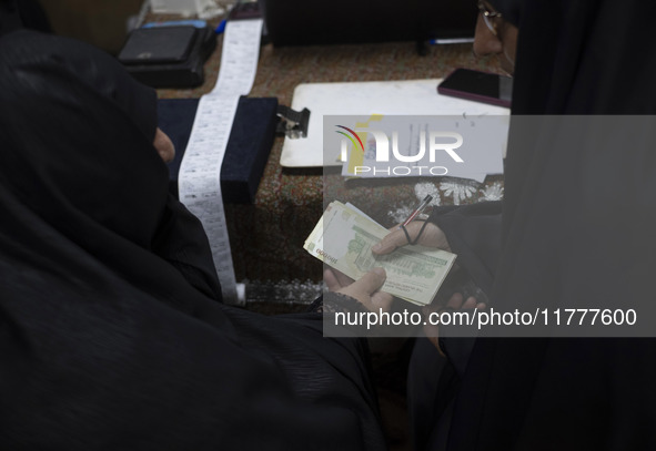 A veiled Iranian woman donates Iranian banknotes during a charity ceremony for donating gold and money to help the Lebanese Resistance Front...