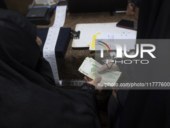 A veiled Iranian woman donates Iranian banknotes during a charity ceremony for donating gold and money to help the Lebanese Resistance Front...