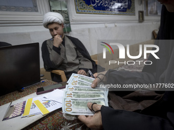 A veiled Iranian woman checks donated U.S. dollar banknotes during a charity ceremony to help the Lebanese Resistance Front and its affected...