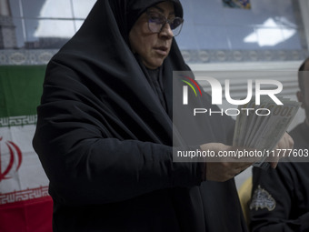 A veiled Iranian woman holds donated U.S. dollar banknotes during a charity ceremony to help the Lebanese Resistance Front and its affected...