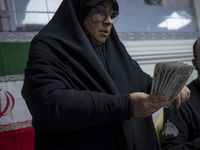 A veiled Iranian woman holds donated U.S. dollar banknotes during a charity ceremony to help the Lebanese Resistance Front and its affected...