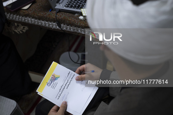 An Iranian cleric holds a signed document with Persian script that reads, ''I donate my gold with the intention of helping the war-torn peop...