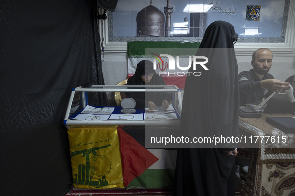 A veiled Iranian woman adjusts gold and jewelry that are donated during a charity ceremony by other veiled women to help the Lebanese Resist...