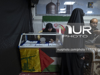 A veiled Iranian woman adjusts gold and jewelry that are donated during a charity ceremony by other veiled women to help the Lebanese Resist...