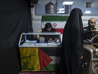 A veiled Iranian woman adjusts gold and jewelry that are donated during a charity ceremony by other veiled women to help the Lebanese Resist...