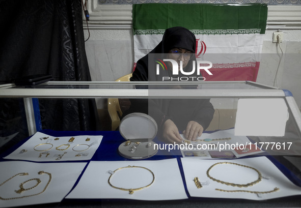 A veiled Iranian woman adjusts gold and jewelry that are donated during a charity ceremony by other veiled women to help the Lebanese Resist...