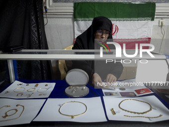 A veiled Iranian woman adjusts gold and jewelry that are donated during a charity ceremony by other veiled women to help the Lebanese Resist...