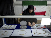 A veiled Iranian woman adjusts gold and jewelry that are donated during a charity ceremony by other veiled women to help the Lebanese Resist...