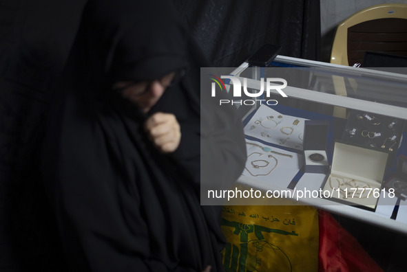 A veiled Iranian woman stands next to gold and jewelry that are donated during a charity ceremony by other veiled women to help the Lebanese...