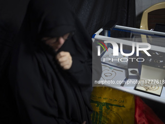 A veiled Iranian woman stands next to gold and jewelry that are donated during a charity ceremony by other veiled women to help the Lebanese...