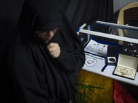 A veiled Iranian woman stands next to gold and jewelry that are donated during a charity ceremony by other veiled women to help the Lebanese...