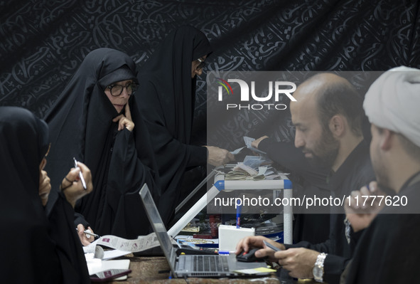 Two veiled Iranian women count donated Iranian banknotes during a charity ceremony to help the Lebanese Resistance Front and its affected pe...