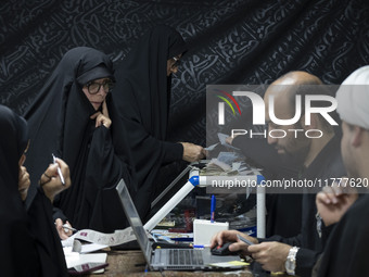 Two veiled Iranian women count donated Iranian banknotes during a charity ceremony to help the Lebanese Resistance Front and its affected pe...