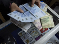 A veiled Iranian woman checks donated Iranian banknotes, while donated U.S. dollar banknotes are pictured during a charity ceremony to help...