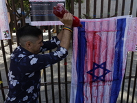 A pro-Palestine activist in Mexico City, Mexico, paints an Israeli flag outside the Memory and Tolerance Museum, where more people demand th...