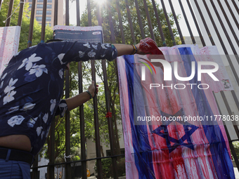 A pro-Palestine activist in Mexico City, Mexico, paints an Israeli flag outside the Memory and Tolerance Museum, where more people demand th...