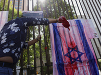 A pro-Palestine activist in Mexico City, Mexico, paints an Israeli flag outside the Memory and Tolerance Museum, where more people demand th...