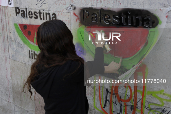 A pro-Palestine activist in Mexico City, Mexico, paints graffiti outside the Memory and Tolerance Museum, where more people demand Claudia S...