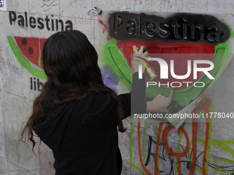 A pro-Palestine activist in Mexico City, Mexico, paints graffiti outside the Memory and Tolerance Museum, where more people demand Claudia S...