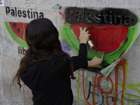 A pro-Palestine activist in Mexico City, Mexico, paints graffiti outside the Memory and Tolerance Museum, where more people demand Claudia S...