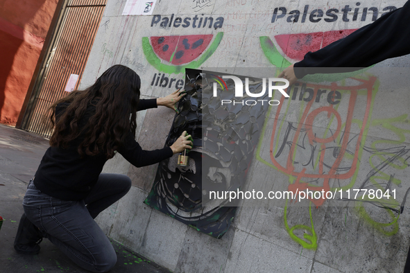 A pro-Palestine activist in Mexico City, Mexico, paints graffiti outside the Memory and Tolerance Museum, where more people demand Claudia S...