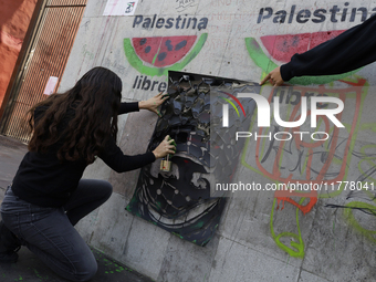 A pro-Palestine activist in Mexico City, Mexico, paints graffiti outside the Memory and Tolerance Museum, where more people demand Claudia S...