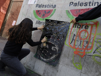 A pro-Palestine activist in Mexico City, Mexico, paints graffiti outside the Memory and Tolerance Museum, where more people demand Claudia S...