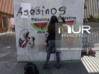 A pro-Palestine activist in Mexico City, Mexico, paints graffiti outside the Memory and Tolerance Museum, where more people demand Claudia S...