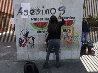 A pro-Palestine activist in Mexico City, Mexico, paints graffiti outside the Memory and Tolerance Museum, where more people demand Claudia S...