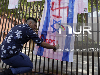 A pro-Palestine activist in Mexico City, Mexico, paints an Israeli flag outside the Memory and Tolerance Museum, where more people demand th...