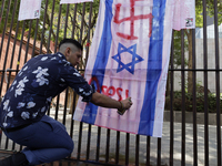 A pro-Palestine activist in Mexico City, Mexico, paints an Israeli flag outside the Memory and Tolerance Museum, where more people demand th...